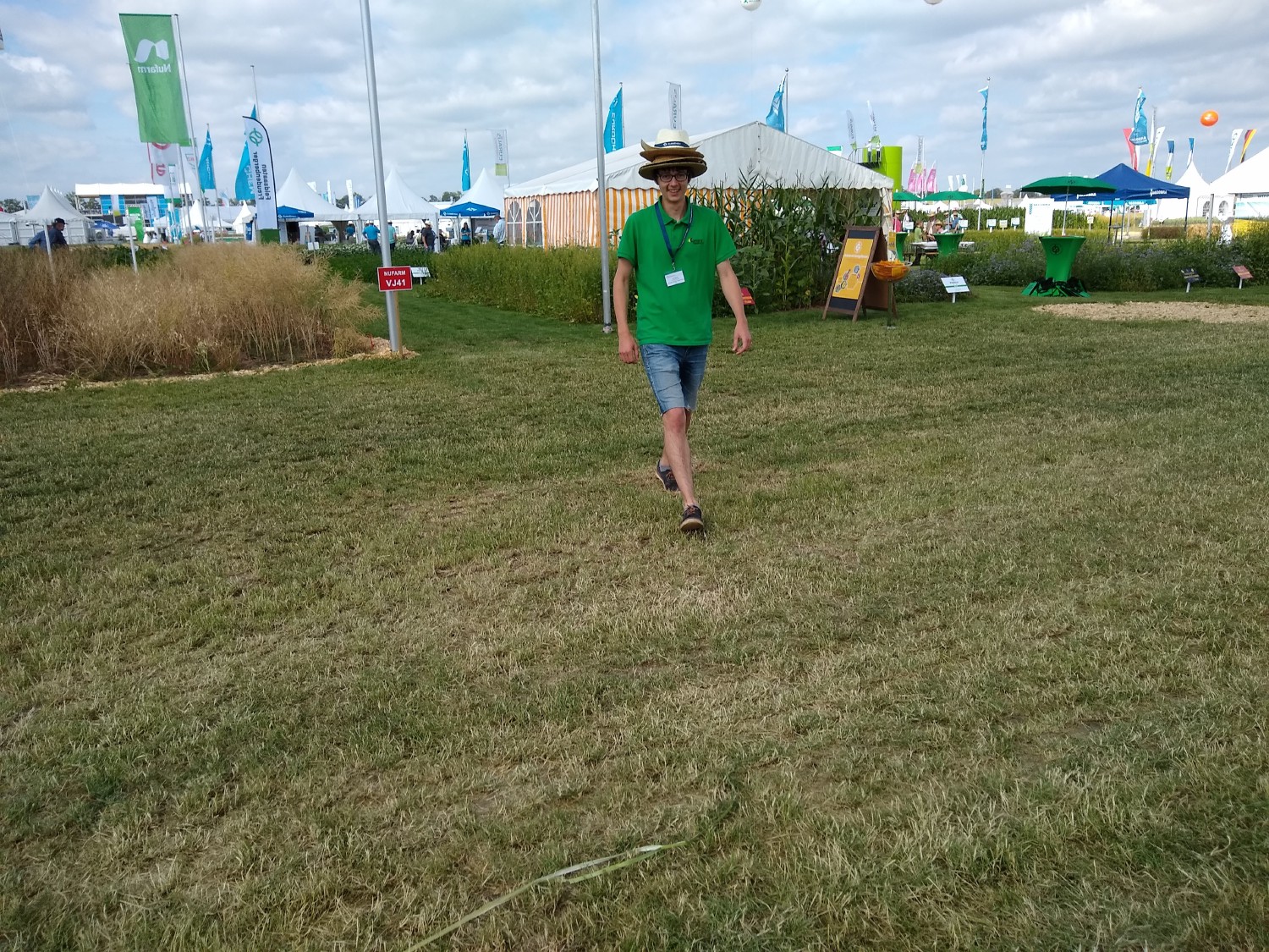 eines unserer Teammitglieder kommt auf die Kamera zugelaufen und hat mehrere Strohhüte übereinander auf